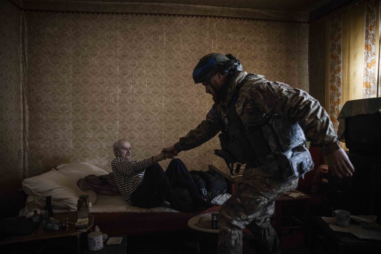 Oleksii Kharkivskyi, head of patrol police in Vovchansk, helps an elderly man to evacuate on May 13.