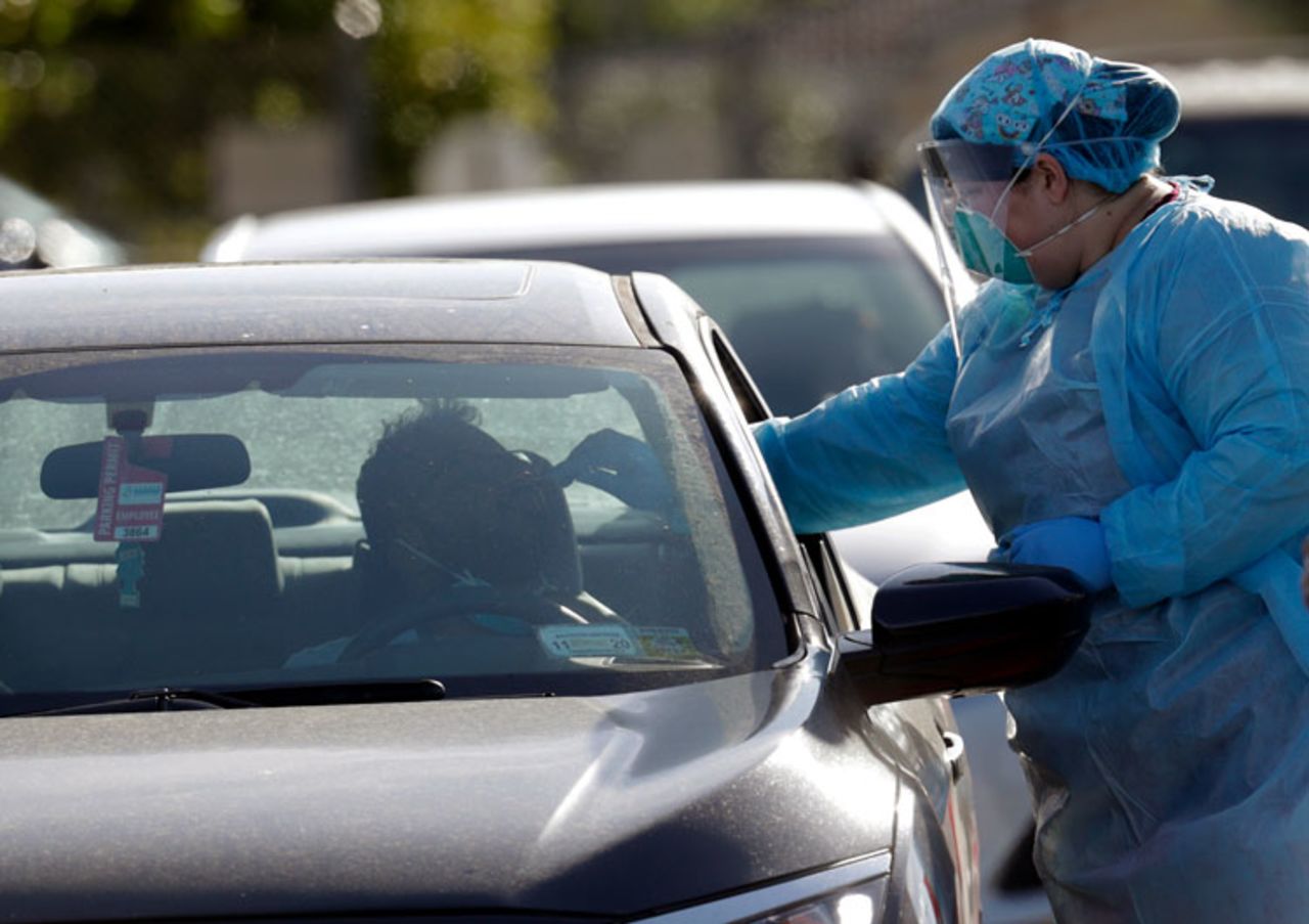 A man is swabbed as he is tested for Covid-19 as vehicles line up at the Doris Ison Health Center, Wednesday, March 18, in Miami.