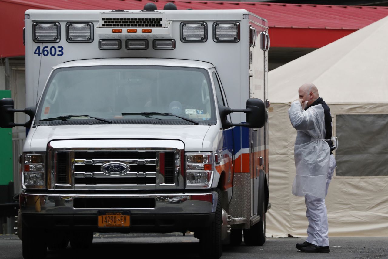 An ambulance attendant adjusts his face mask before transferring a patient to the emergency department of Elmhurst Hospital Center in New York on March 28.