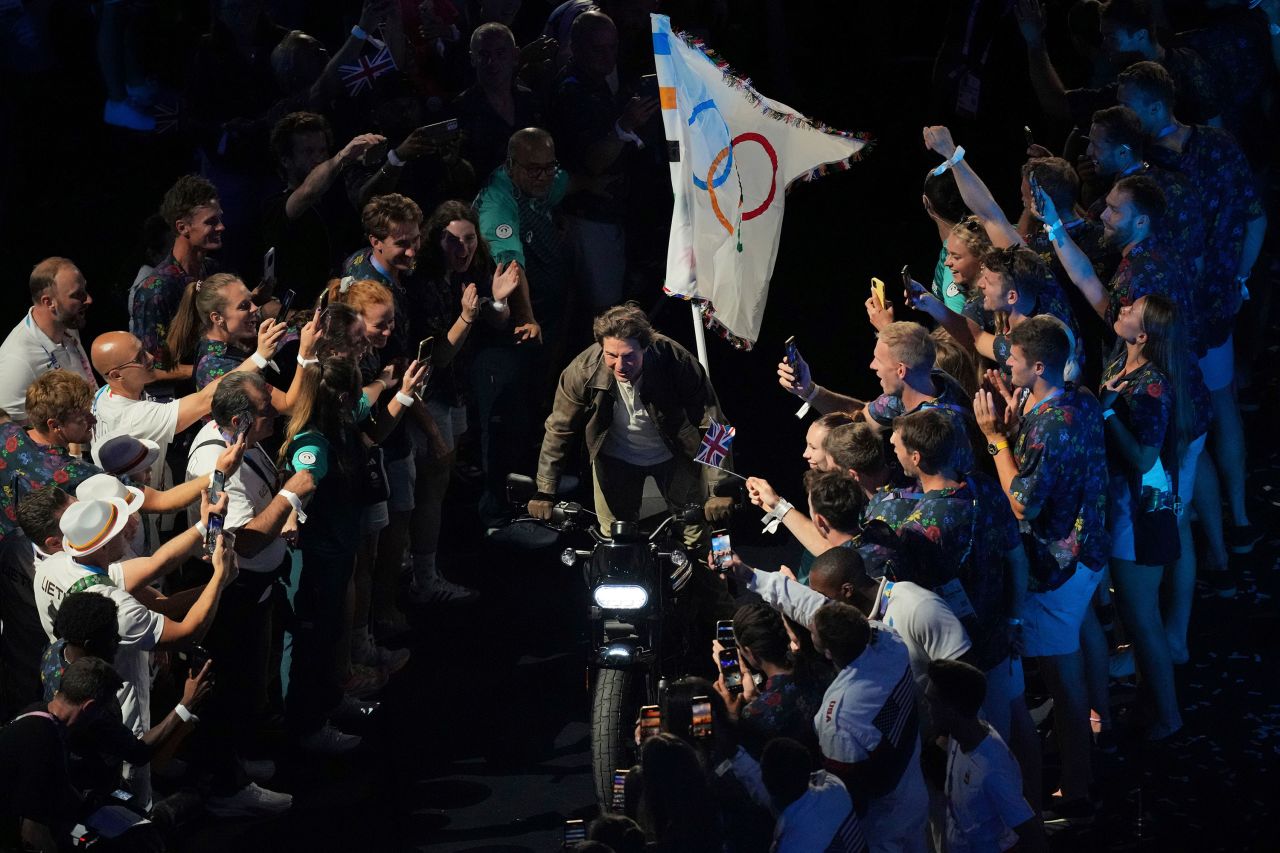 Actor Tom Cruise carries the Olympic flag on a motorcycle near the end of the ceremony.