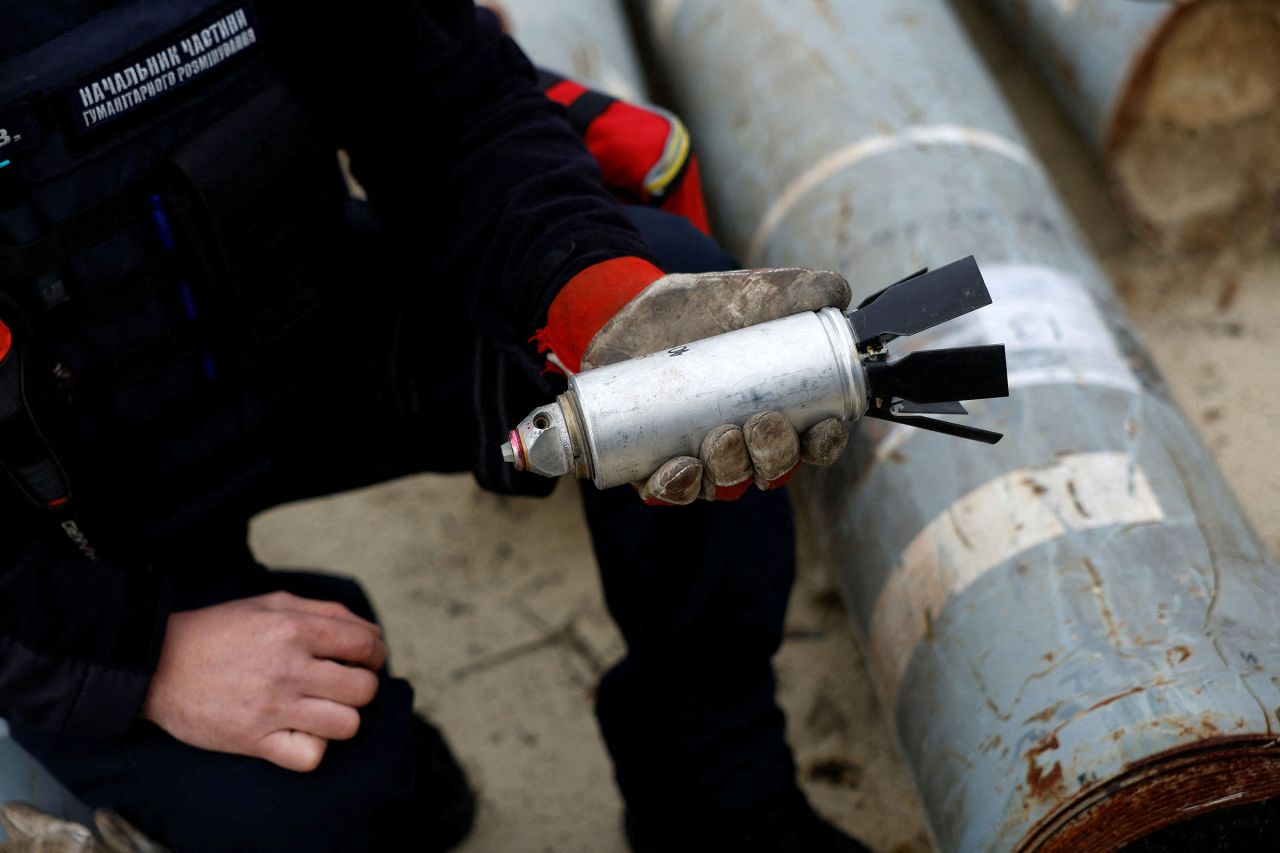 In this October 2022 photo, Ukrainian military serviceman Igor Ovcharruck holds a defused cluster bomb from an MSLR missile, among a display of pieces of rockets used by Russian army, that a Ukrainian munitions expert said did not explode on impact, in the region of Kharkiv, Ukraine.