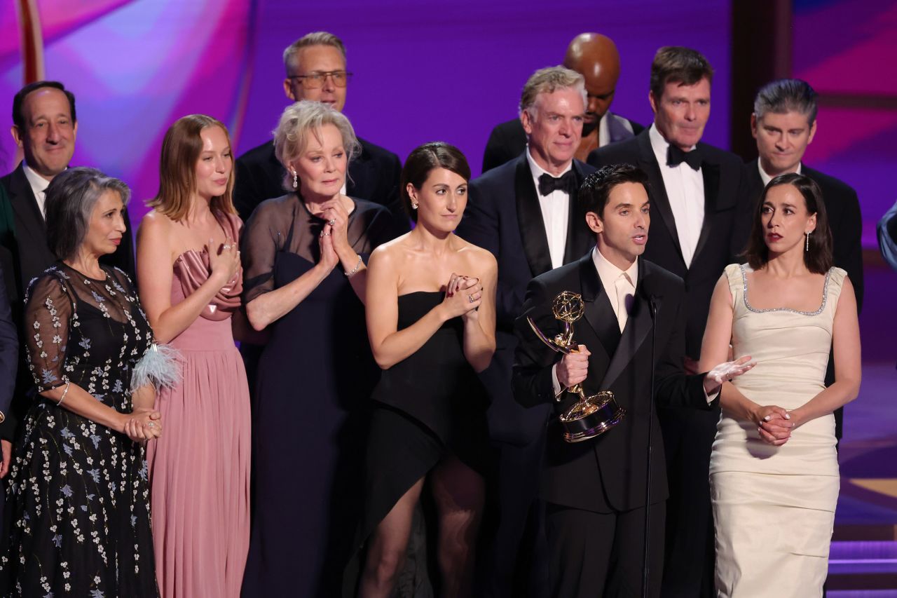 Paul W. Downs, front, and the cast and crew of "Hacks" accept the award for outstanding comedy series. 