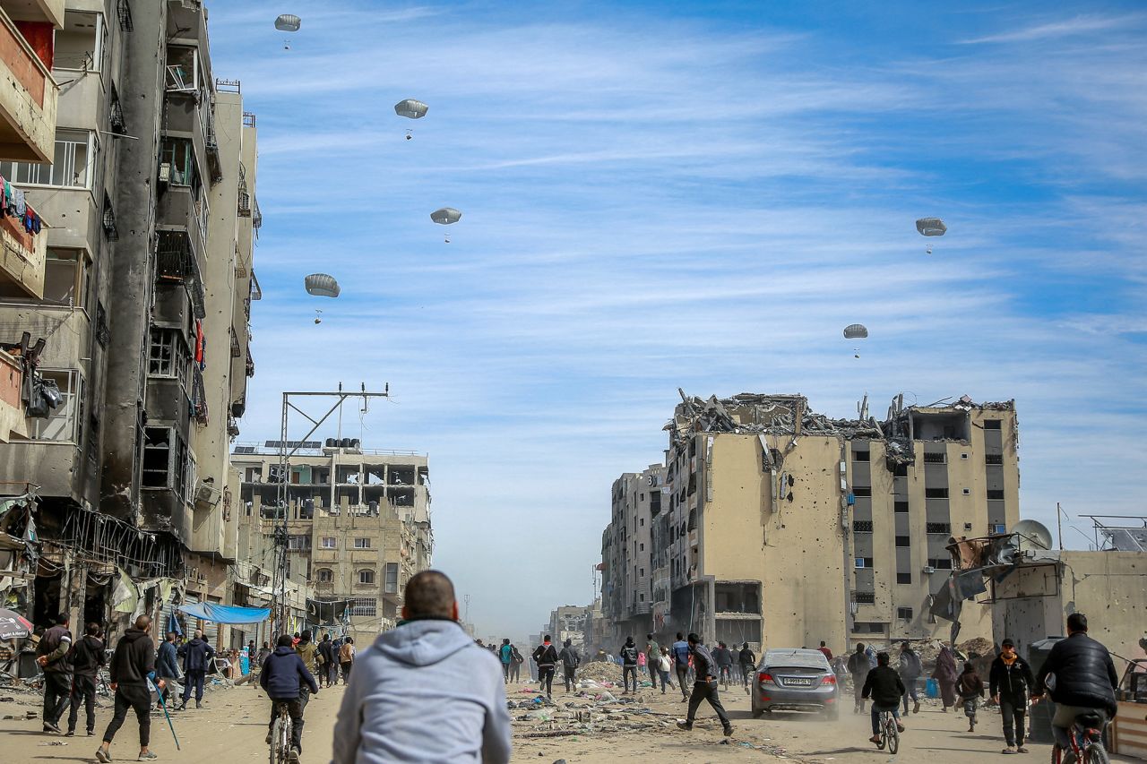 Palestinians run along a street as humanitarian aid is airdropped in Gaza City on March 1.