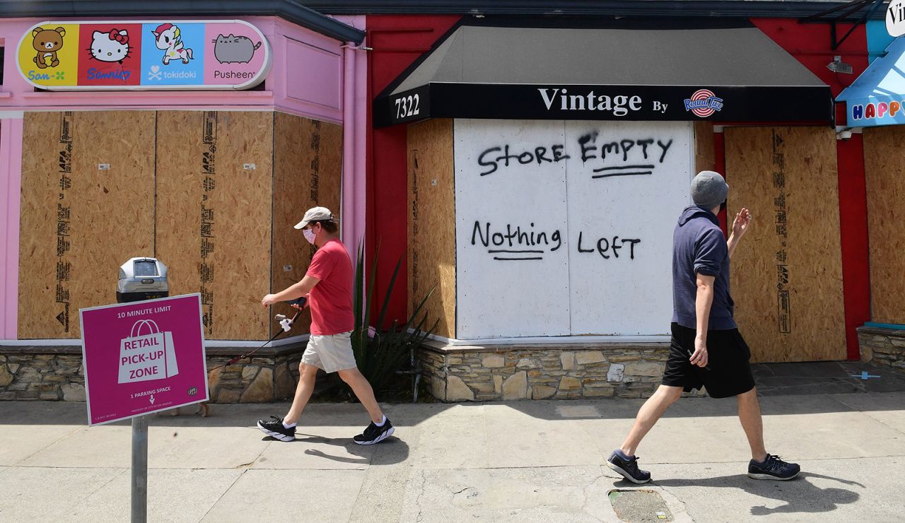 Pedestrians walk past boarded up storefronts on Melrose Avenue in Los Angeles on June 1.