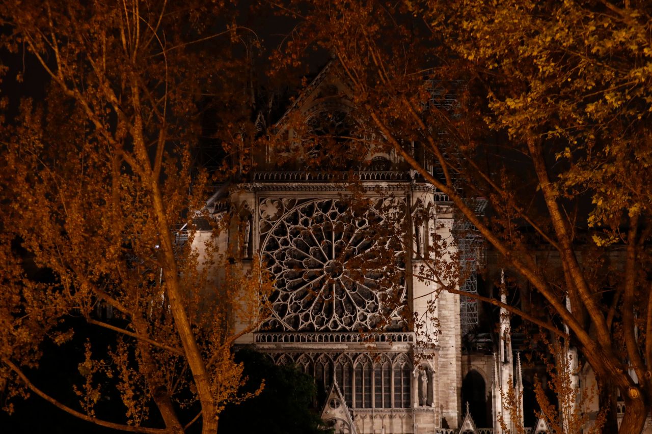 Firefighters (L) work to contain a fire near the north rose window at the cathedral.