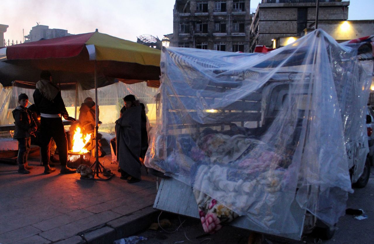 People who evacuated their homes stand around a fire in Aleppo on Wednesday.