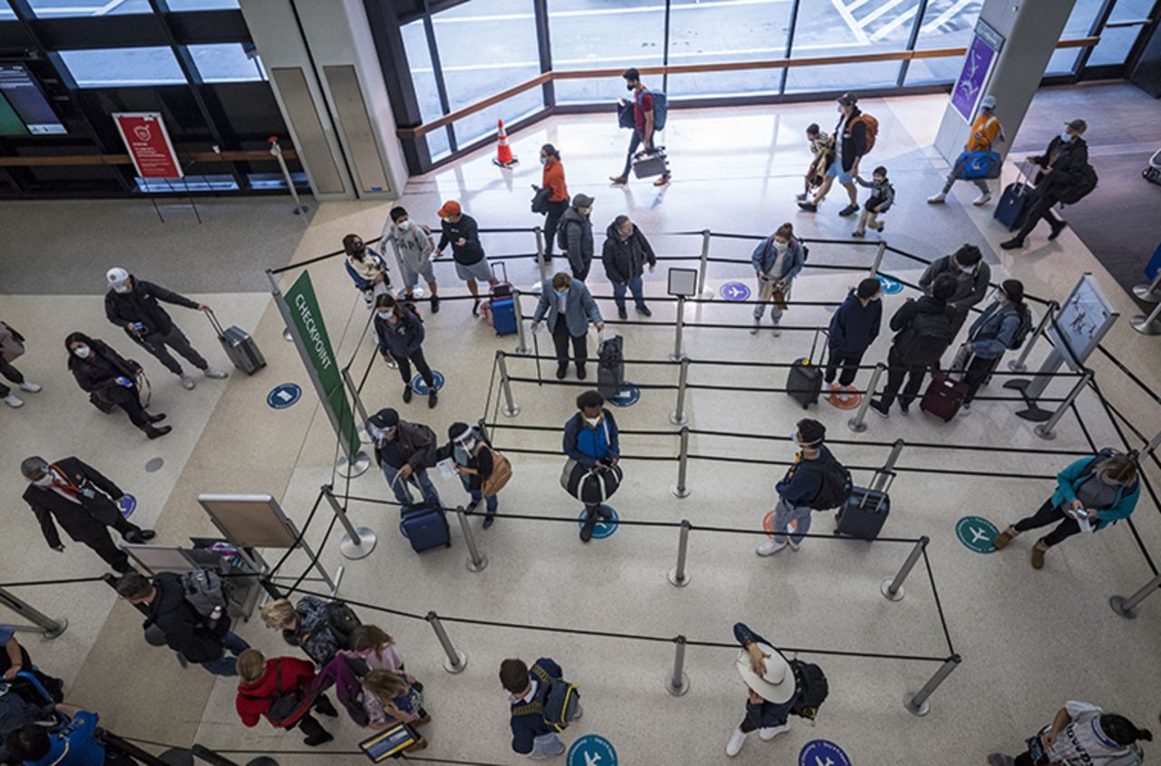 Travelers wearing protective masks wait in line to go through security at San Francisco International Airport (SFO) in San Francisco, California, U.S., on Monday, Nov. 24, 2020. 