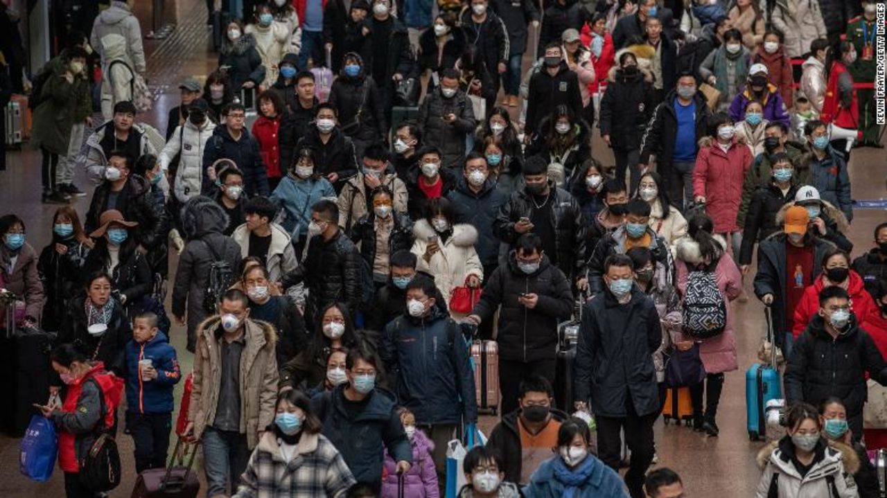 Chinese passengers, most wearing masks, arrive to board trains before the Lunar New Year at a Beijing railway station.