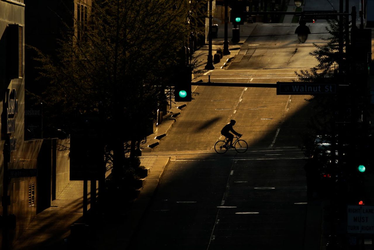 A man on a bicycle crosses an empty downtown street in Kansas City, Missouri on Wednesday, April 15, while stay-at-home orders continue in the state and much of the rest of the country as part of an effort to curb the spread of the new coronavirus.