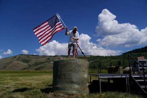 Campaign worker Shannon McCormick uses a stake to place an American flag on top of a hay bale prior to a gathering for Rep. Liz Cheney on Tuesday in Jackson, Wyoming.