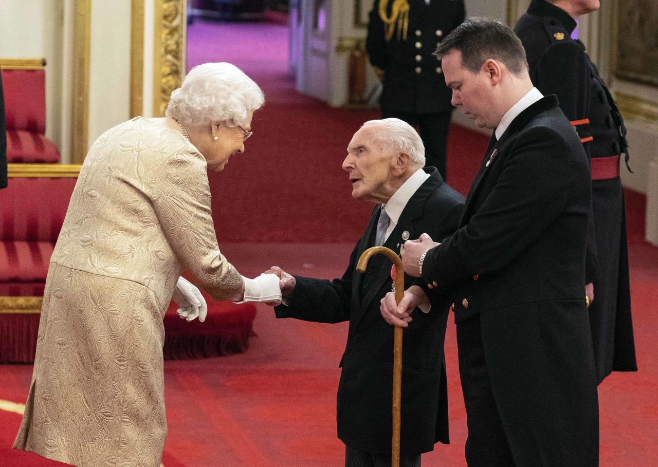 Britain's Queen Elizabeth wears gloves as she awards the MBE (Member of the Order of the British Empire) to Harry Billinge, during an investiture ceremony at Buckingham Palace in London on Tuesday.