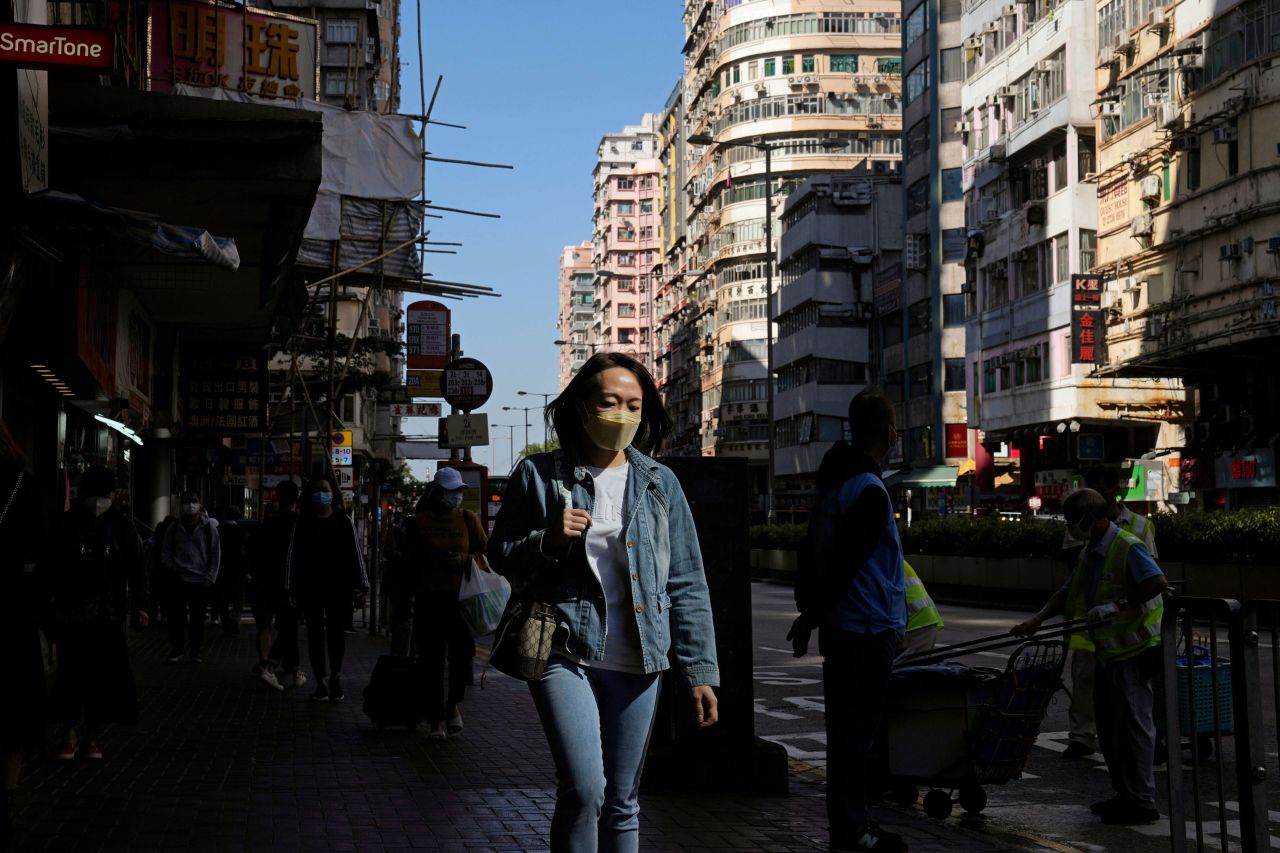 A woman wearing face a mask, walks down a street in Hong Kong, Nov. 29, 2021. 