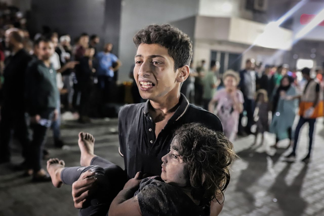 A young boy carries a child injured in the blast to the Al-Shifa Hospital in Gaza City.