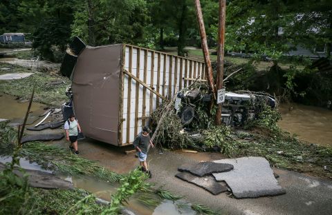 Garland Combs walks past a car and garage that was swept downstream near the muddy Grapevine Creek in Perry County on July 28.