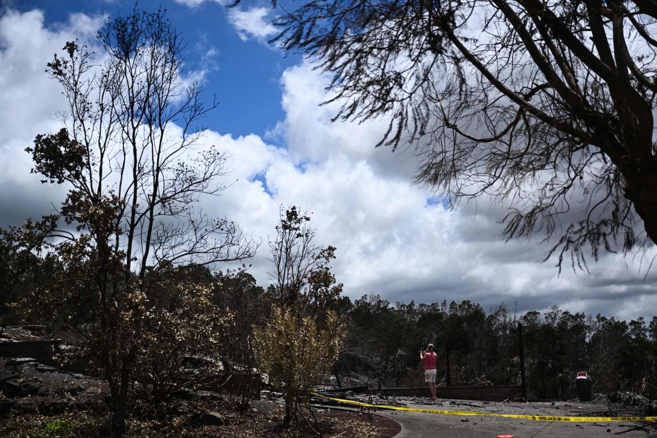 A caretaker photographs the site of a home destroyed by the Maui wildfires in Kula on Sunday.