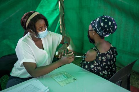 A healthcare worker administers the Johnson and Johnson vaccine to a woman outside a polling station at the Kopanong Hall in Soweto, on November 1st, 2021, during South Africa's local elections. 