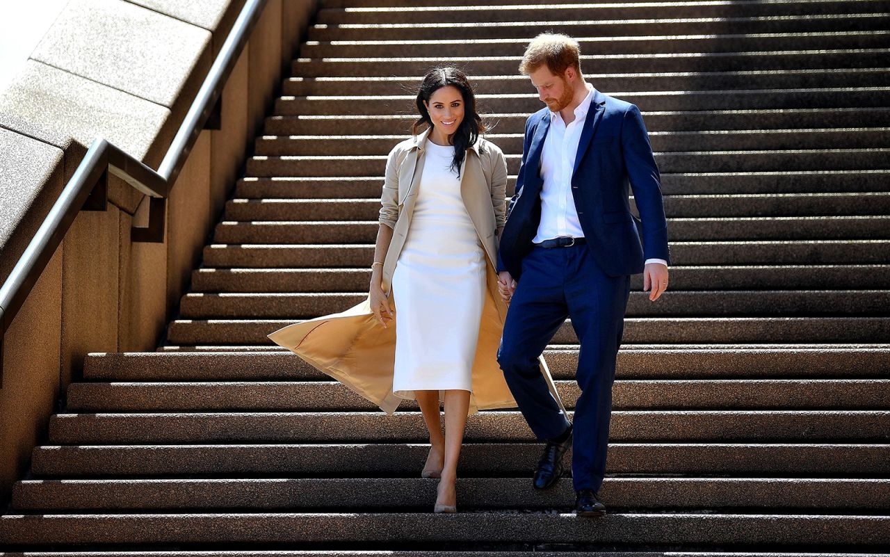 Britain's Prince Harry and his wife Meghan walk down the stairs of the iconic Opera House to meet people on October 16, 2018.