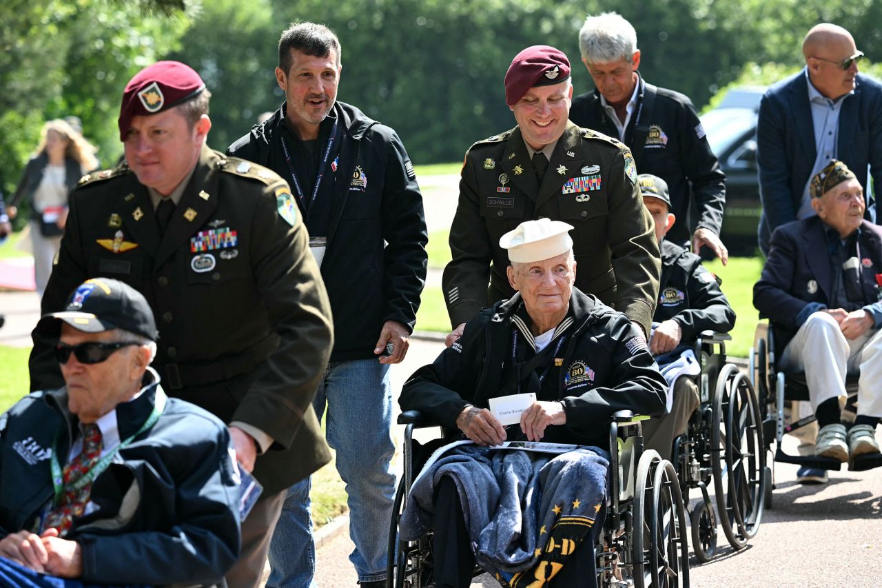 US servicemen escort US WWII veterans in wheelchairs at the Normandy American Cemetery and Memorial in Colleville-sur-Mer in northwestern France, on June 6.