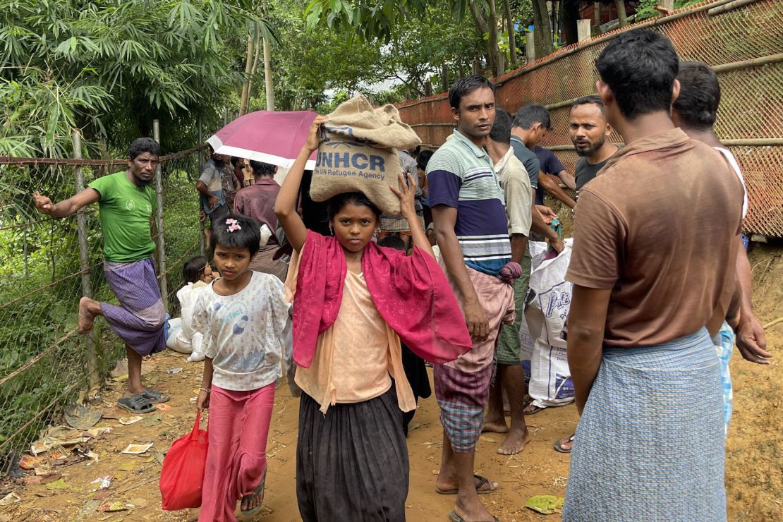 A young girl balances a sack of UNHCR supplies on her head along a roadway in Kutupalong.