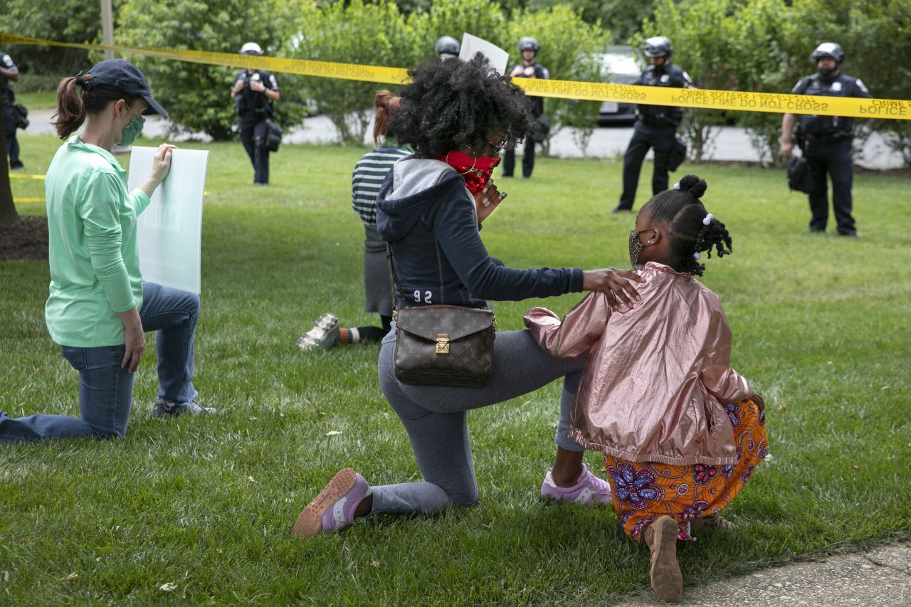 Ericka Ward-Audena, of Washington, puts her hand on her daughter Elle Ward-Audena, 7, as they take a knee in front of a police line during a protest of President Trump's visit to the St. John Paul II National Shrine on June 2, 2020, in Washington.