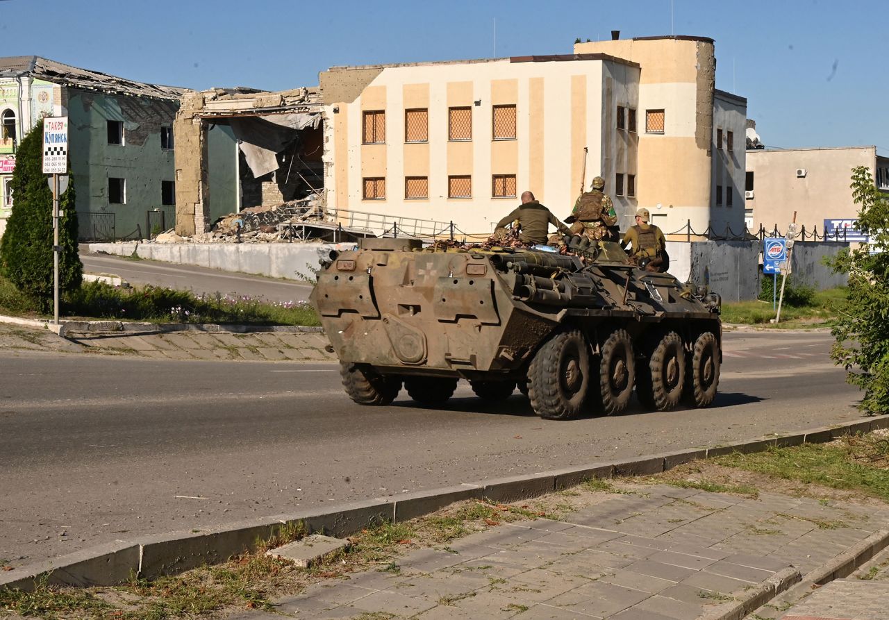 Ukrainian servicemen ride atop of an armored personel carrier past a destroyed building in the town of Kupiansk, Kharkiv region, Ukraine, on August 17.