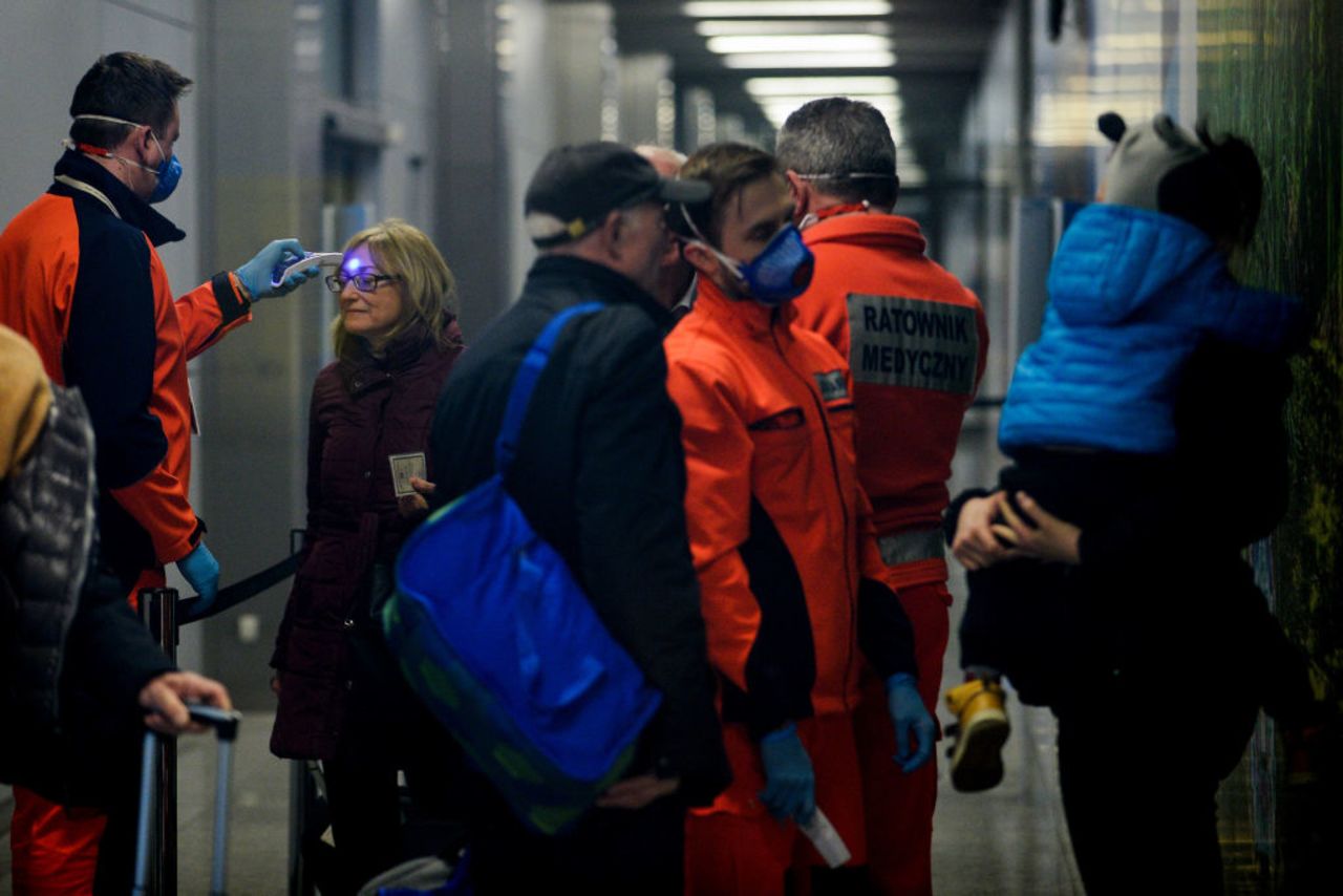 A health worker screens the temperature of a passenger arriving at Krakow International Airport on Wednesday in Krakow, Poland.