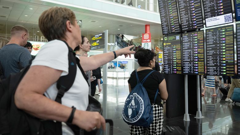 BARCELONA, SPAIN - JULY 19: Passengers look at a screen displaying delayed flights at Barcelona Airport on July 19, 2024 in Barcelona, Spain. Businesses, travel companies and Microsoft users across the globe were among those affected by a tech outage today. (Photo by David Ramos/Getty Images)