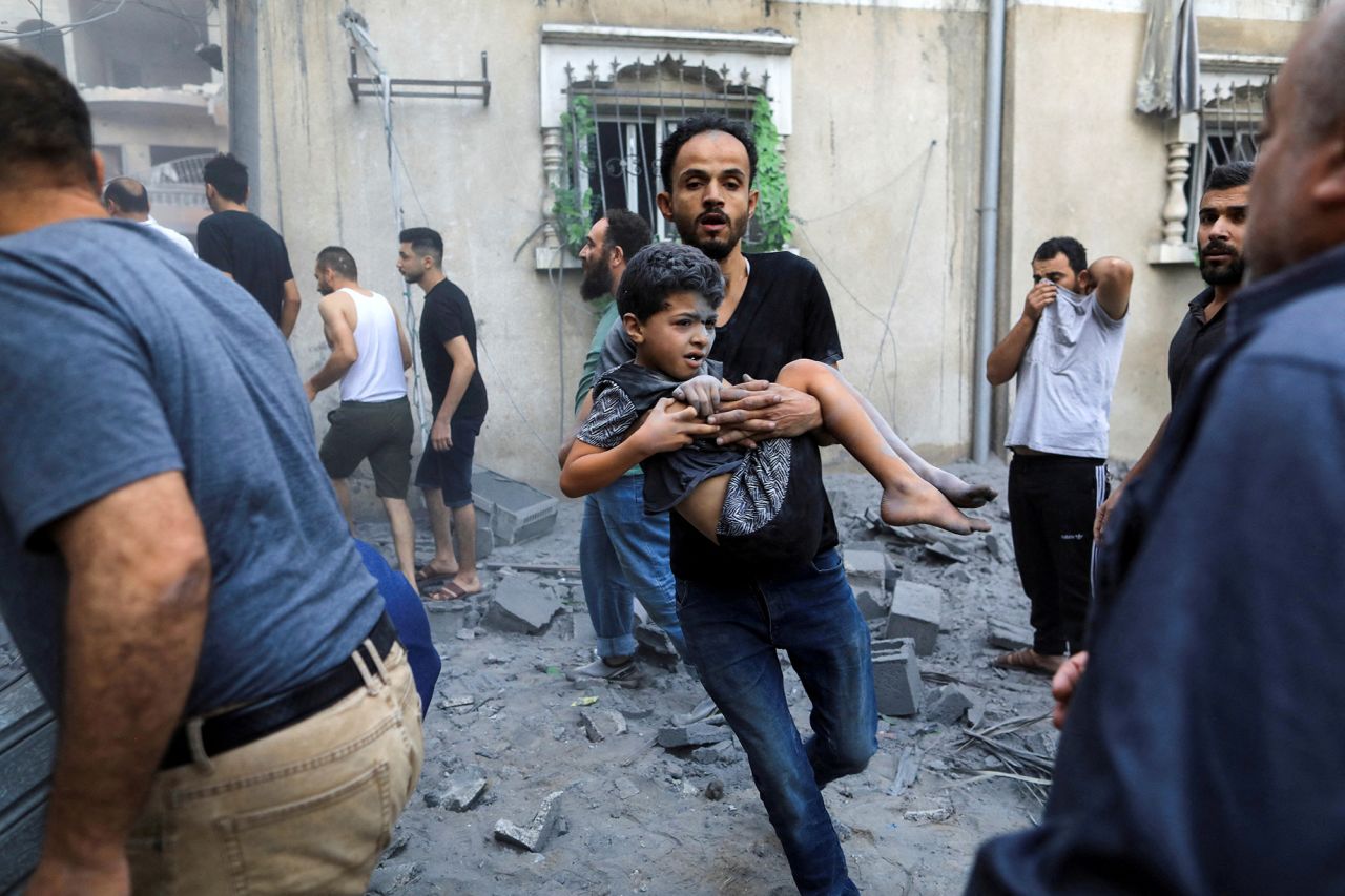 A man carries a wounded child at the site of an Israeli strike in Khan Younis, southern Gaza, on October 19.