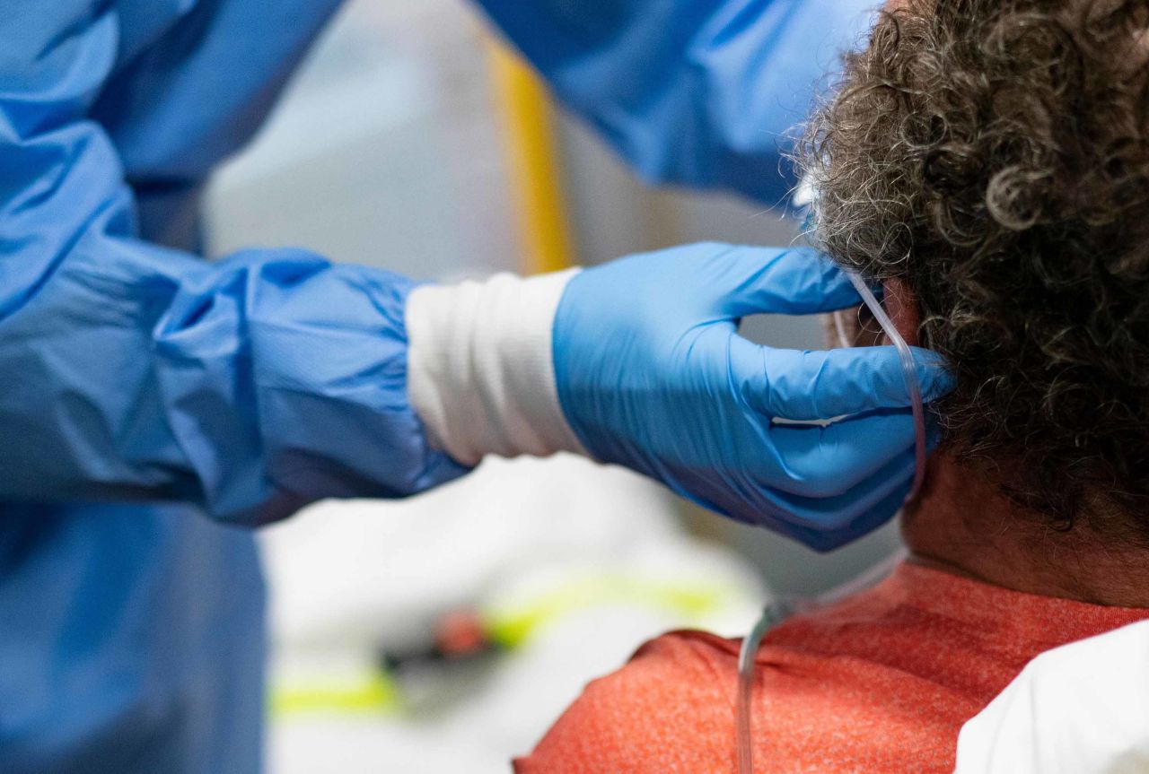 A firefighter with Anne Arundel County Fire Department places oxygen tubes on a suspected COVID-19 patient as he is transported hospital on May 3, in Glen Burnie, Maryland.