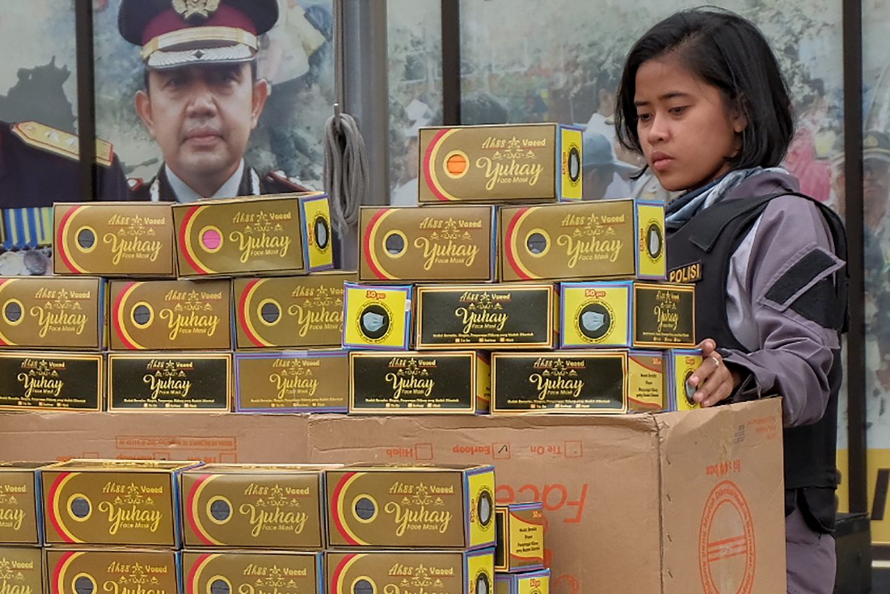 An Indonesian police officer stands next to seized boxes of face masks prior to a press conference at the North Jakarta police headquarters in Jakarta on Friday.