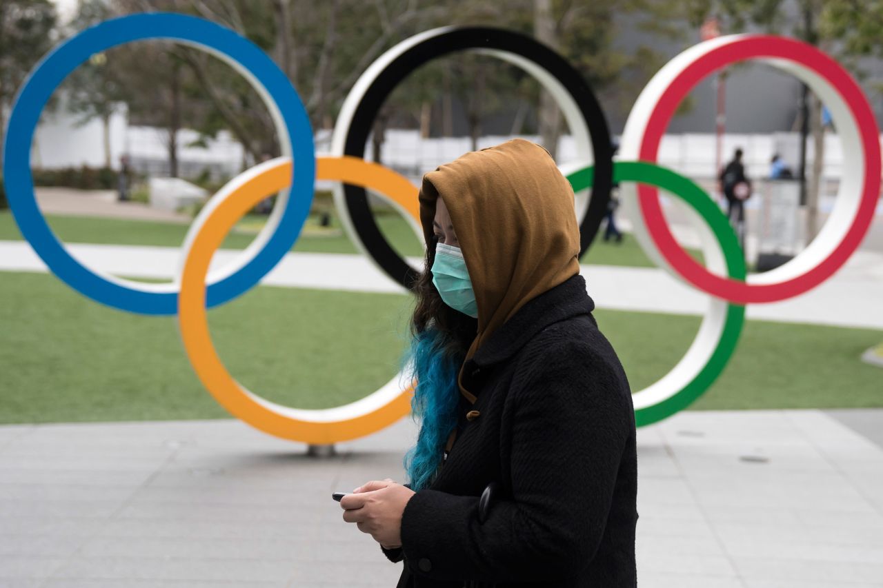 A woman walks past the Olympic rings in front of the new National Stadium, on February 26, in Tokyo.