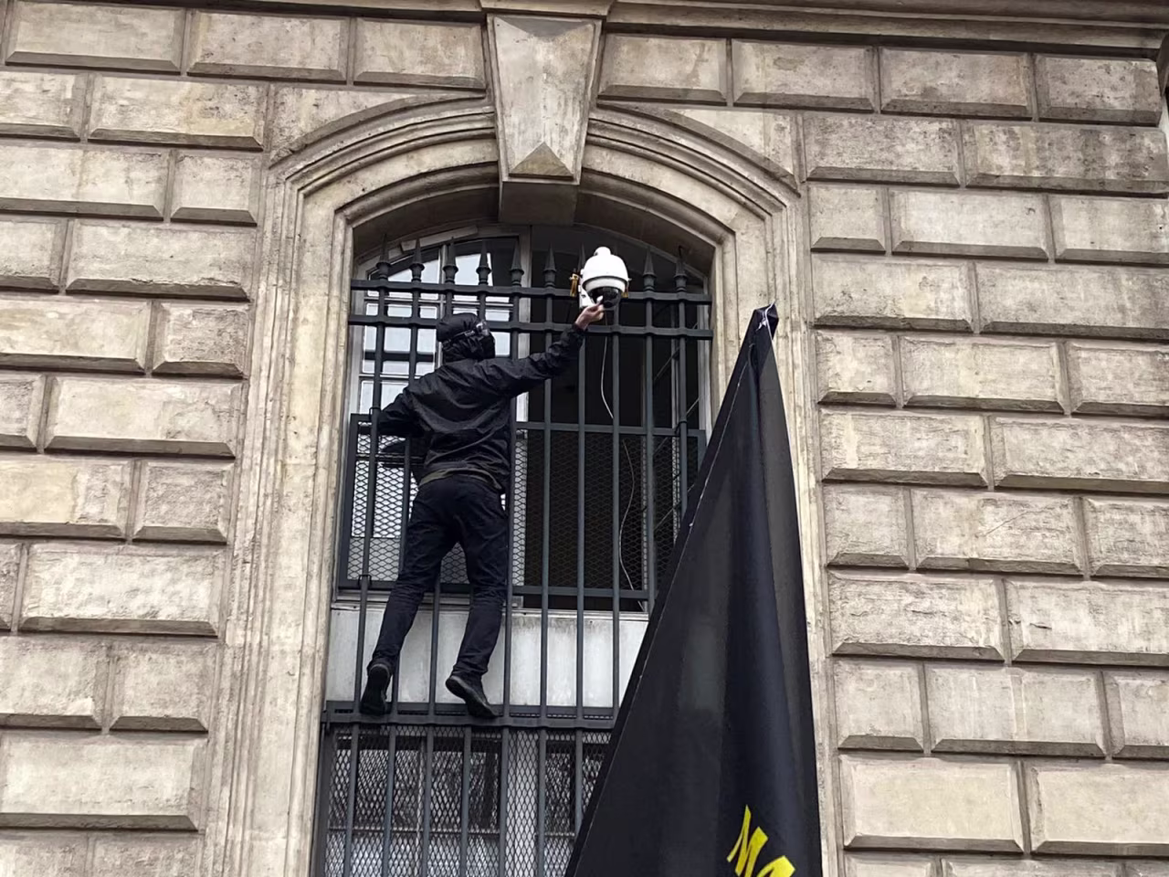 A protester, clad in black, destroyed a security camera.