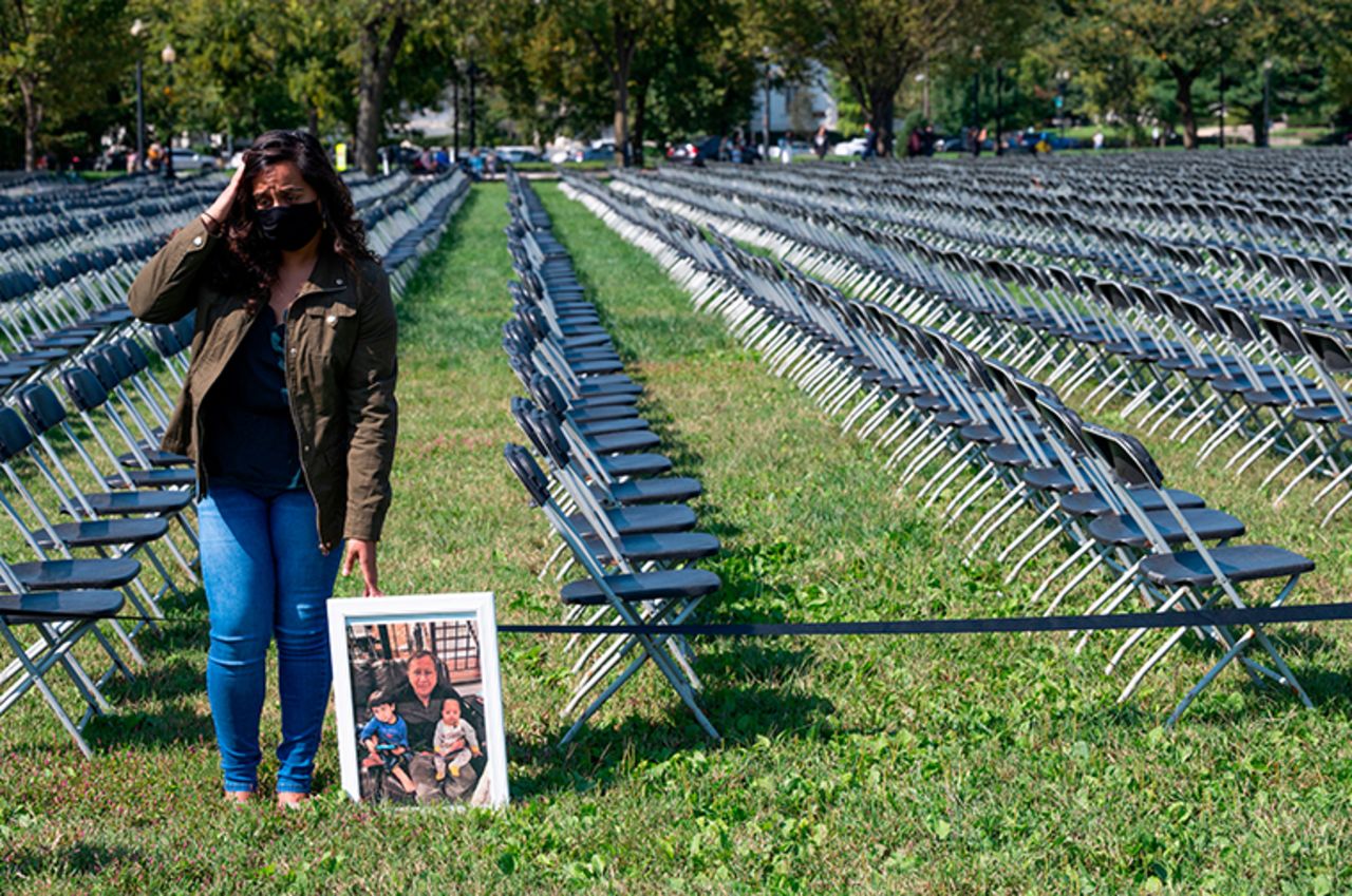 Naeha Quasba reacts as she holds a picture of her father, Ramasha Quasba, who died from coronavirus as she stands near empty chairs on display to represent the 200,000 lives lost due to COVID-19 at the National COVID-19 Remembrance, on the ellipse behind the White House in Washington, DC, on October 4, 2020.?