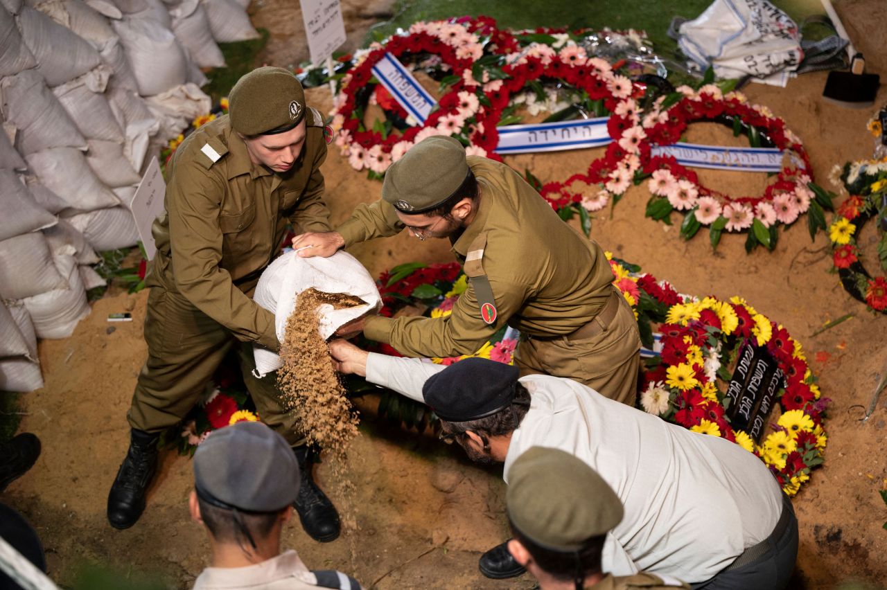 Israeli Defense Forces soldiers drop dirt on the grave of their comrade Noam Elimeleh Rothenberg at Mount Herzel Cemetery during his funeral in Jerusalem on October 10, 2023.