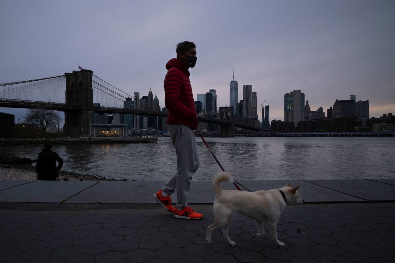 A man wears a mask while walking his dog in Brooklyn Bridge Park on Tuesday, April 14.