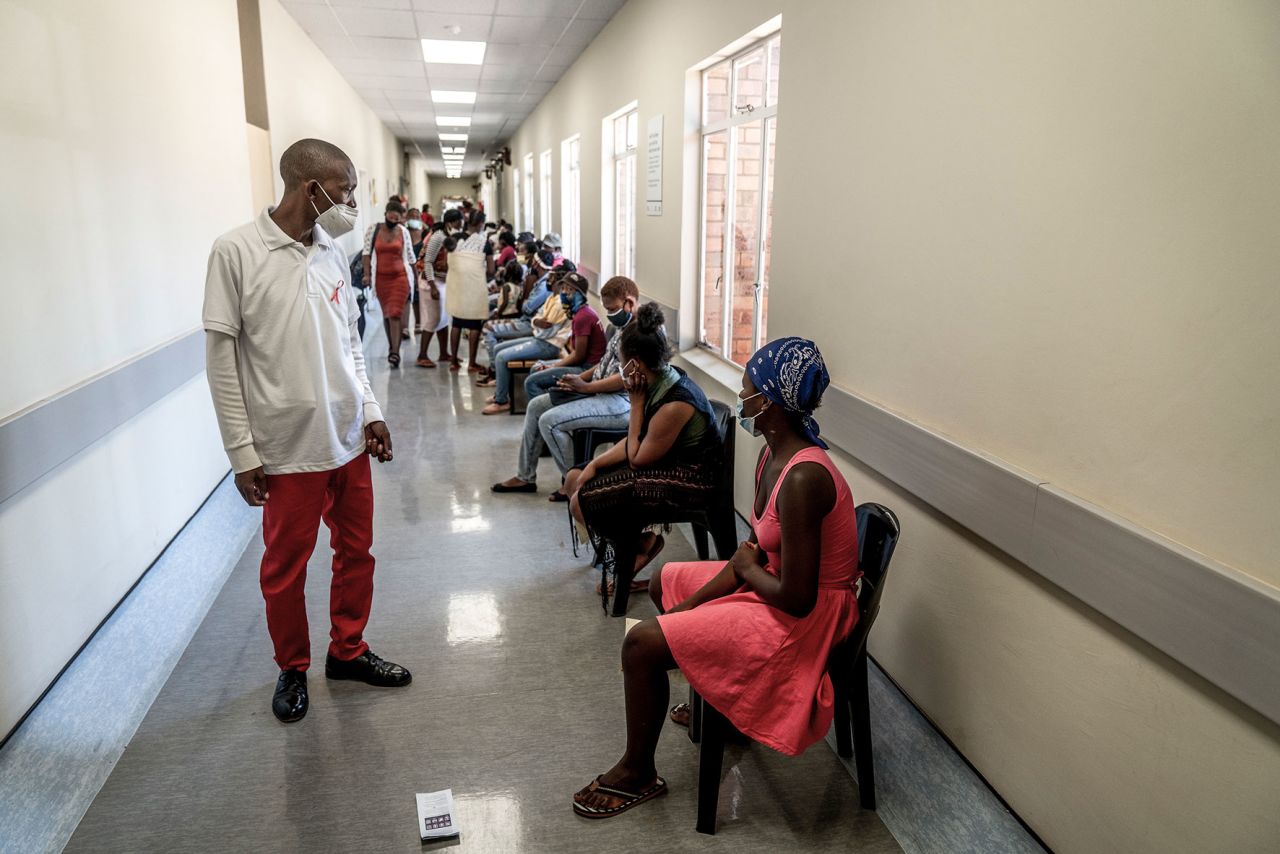A hospital worker ensures people practice social distancing as they wait in line to get vaccinated against COVID-19 at the Lenasia South Hospital, near Johannesburg, South Africa, Dec. 1, 2021