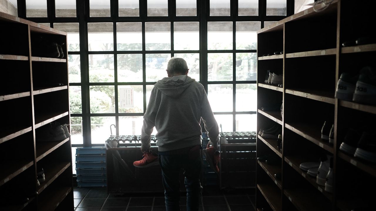 A resident picks up his shoes at a temporally shelter for internet-cafe dwellers at the Kanagawa Budokan martial arts gymnasium in Yokohama, Japan, on April 22. 