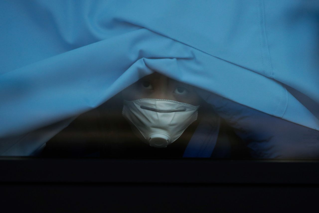 A passenger who disembarked from the quarantined Diamond Princess cruise ship peeks out of a bus window Wednesday in Yokohama, Japan.