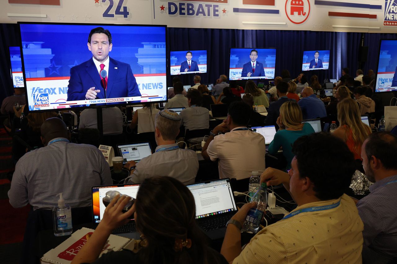 Reporters watch Republican presidential candidate, Florida Gov. Ron DeSantis speak on television during the first debate of the GOP primary season hosted by FOX News at the Fiserv Forum on August 23 in Milwaukee. 