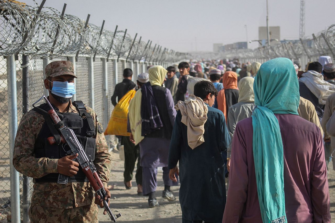 A Pakistani soldier stands guard as Afghans walk along fences after arriving in Pakistan through the Pakistan-Afghanistan border crossing point in Chaman on August 26. 