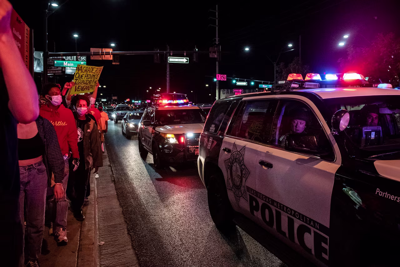 A police officer looks outside the car window as people march, on June 1, in downtown Las Vegas.