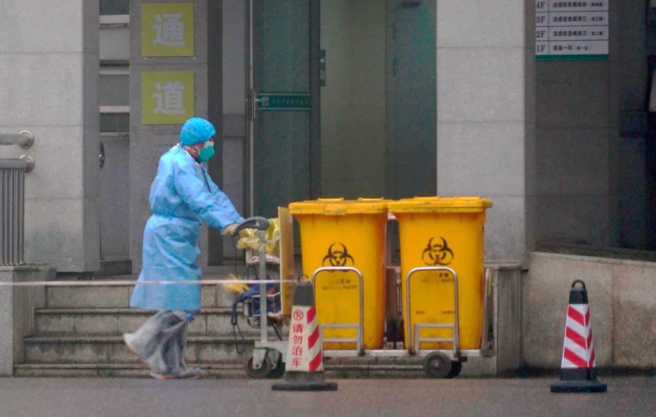 Staff move bio-waste containers past the entrance of the Wuhan Medical Treatment Center.