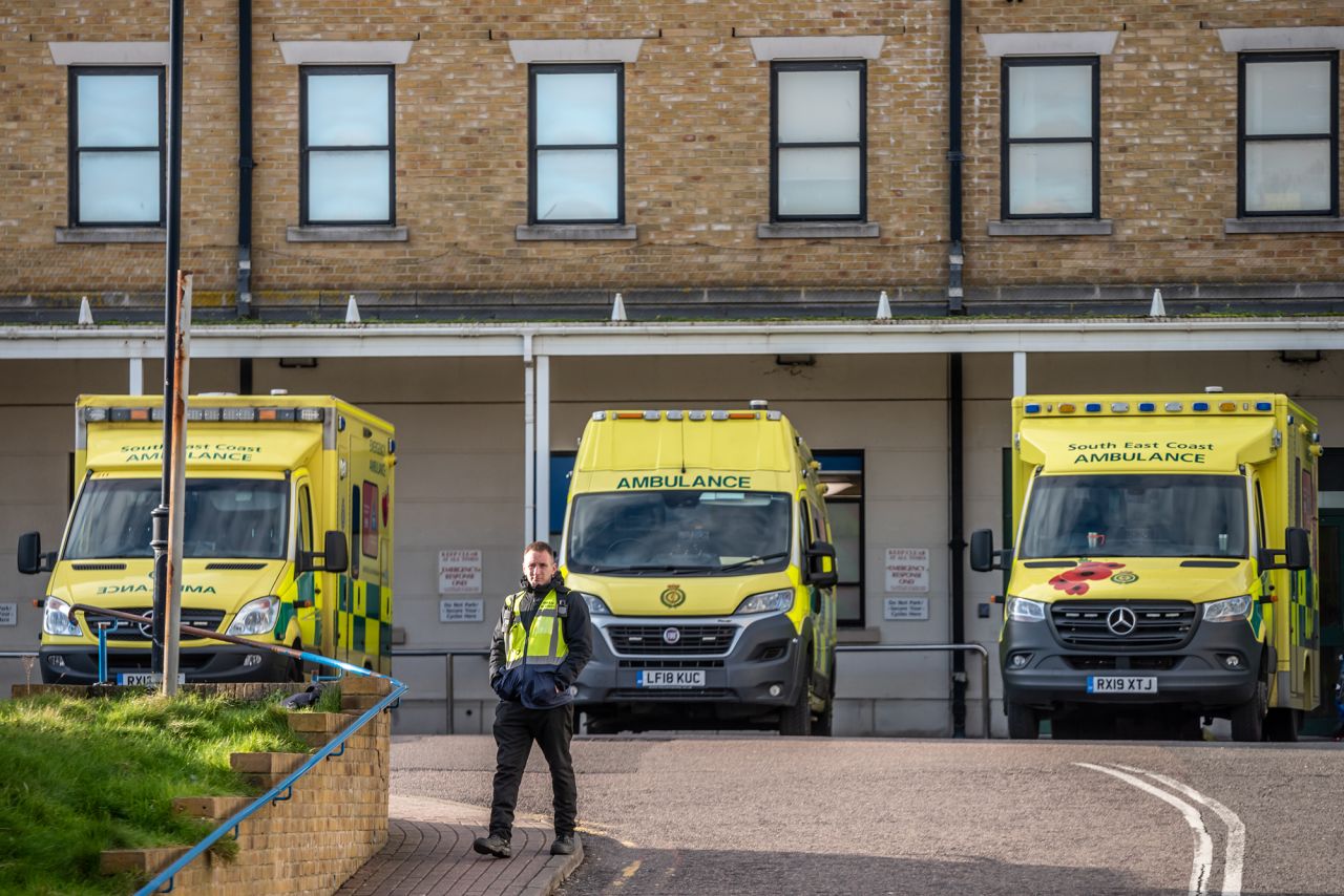 A man walks past ambulances parked outside the Royal Sussex County Hospital where a third person has tested positive for coronavirus in the UK on February 6.