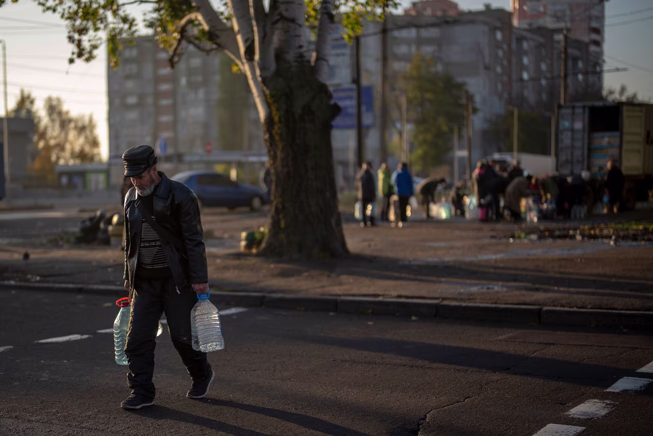 A man carries plastic bottles after refilling them at a tank in Mykolaiv on October 24. 