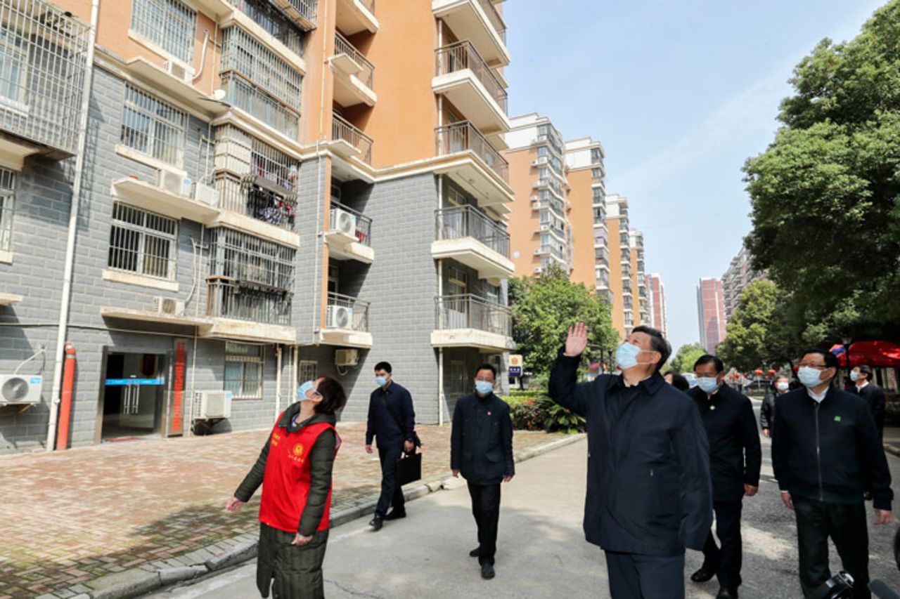 In this Tuesday, March 10, photo released by Xinhua News Agency, Chinese President Xi Jinping waves to residents who are quarantined at home as he pays a visit to a community in Wuhan in central China's Hubei province. 