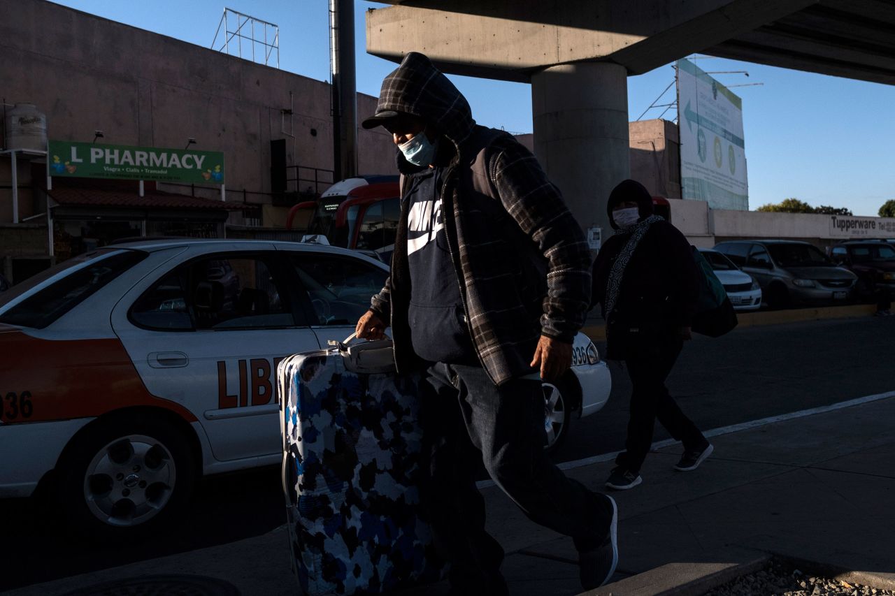 A couple wearing protective masks walks towards the El Chaparral crossing port on the US/Mexico Border in Tijuana, Mexico, on February 29.