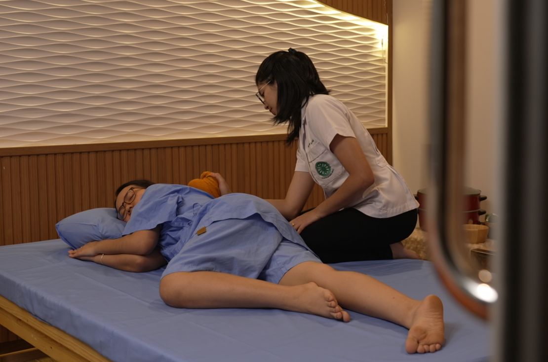 A woman receiving a massage treatment using an herbal compress.