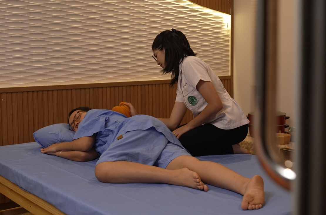 A woman receives a massage treatment with a herbal compress.