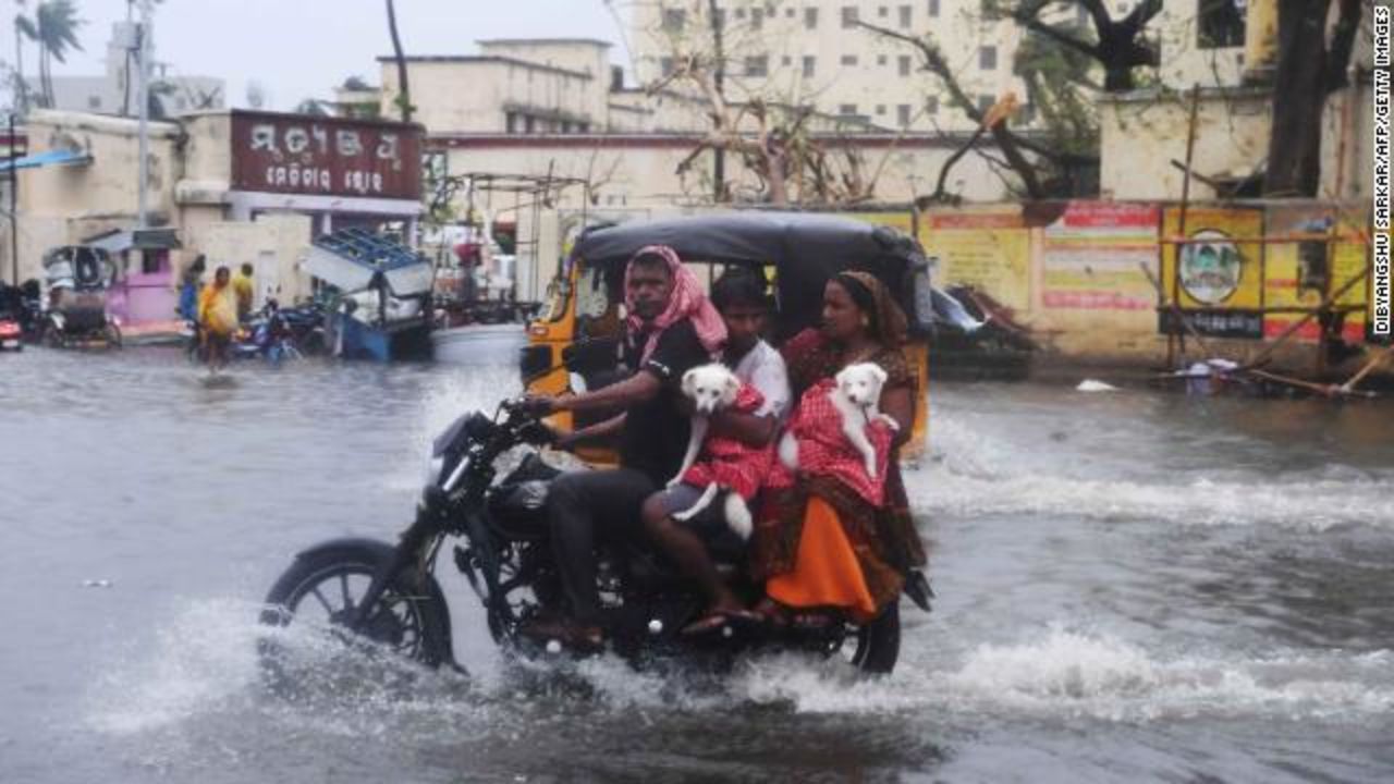 Indian residents ride on a bike along a flooded road after Cyclone Fani landfall in Puri on May 3, 2019.?