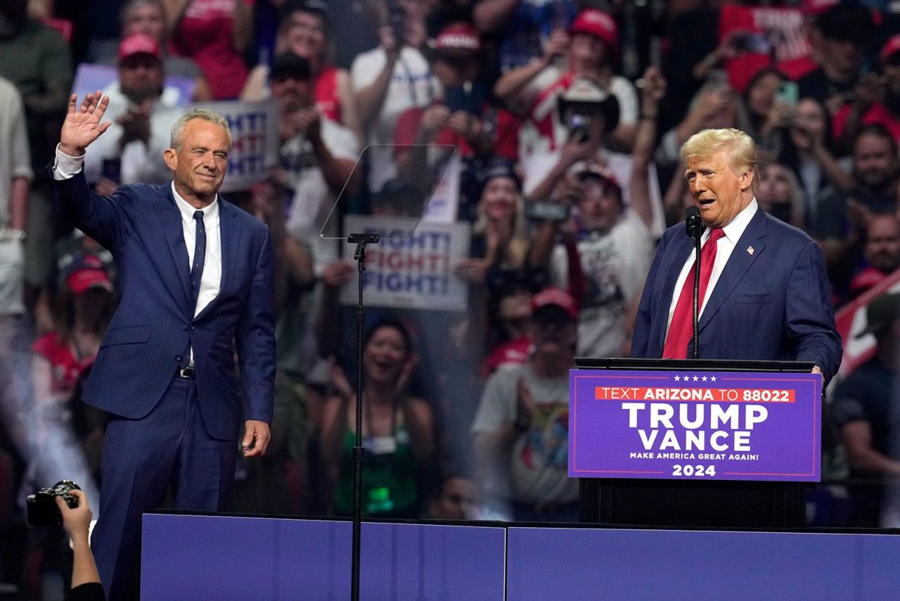 Robert F. Kennedy Jr., left, waves to the crowd as former President Donald Trump speaks at a campaign rally in Glendale, Arizona on August 23.